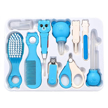 A baby grooming kit in a white plastic tray, featuring various blue and white pet-adjacent tools including a brush, comb, nail clipper, scissors, and a bottle-shaped lube dispenser, all with cute bear and cat face details.