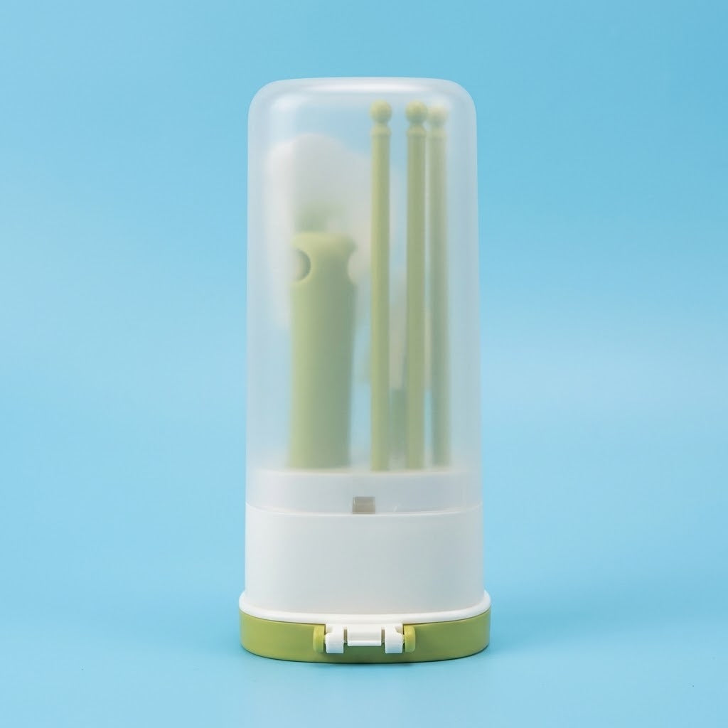 A small cylindrical storage container with a translucent clear top, white base, and light green bottom, holding several pale green tools or accessories, photographed on a smooth light blue background.