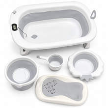 A baby bath set arranged on a white background, including a foldable bathtub, a small bucket, a cup with handle, a bowl, a drain mat, and a digital temperature display.