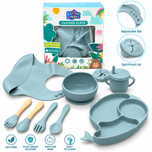 Little Luvs silicone baby feeding set in a dusty blue-gray color, including a silicone plate, bib, bowl, sippy cup, utensils, and the retail packaging box, displayed on a clean white background with feature callout graphics.